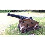 A late 18th/early 19th century iron cannon on a common naval oak gun carriage with securing