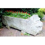 A 19th century hewn stone trough, one end carved with lion mask, open mouthed, with full mane,