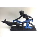 An Art Deco stylized painted plaster statue of a naked woman restraining a German Shepherd dog,