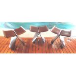 A set of three bentwood, possibly ebony veneered, ply stools, designed by Sori Yanagi, with brass