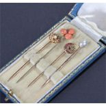 Four cased stick pins, to include a pearl example, a crescent moon example, a coral example and