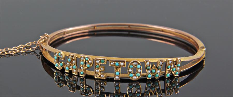 9 carat gold Capetown bangle, the letters set with turquoise and pearl, 6.5cm wide, 9.7 grams