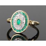 18 carat gold emerald and diamond set ring, the oval head with central emerald flanked with diamonds