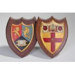 Two heraldic shields, the polychrome painted shield device backed on an shield shape frame, 20cm