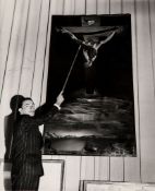 DALI, SALVADOR - Black and white photograph of Salvador Dali pointing at his painting Black and