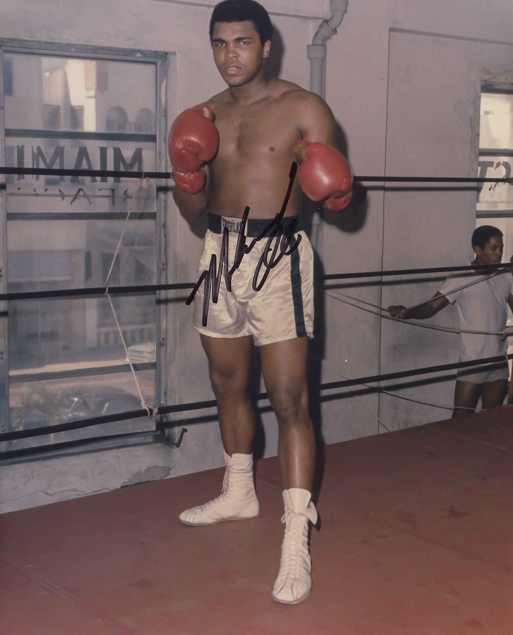 ALI, MUHAMMAD - Glossy full length photograph of Muhammad Ali posing by the ropes... Glossy full