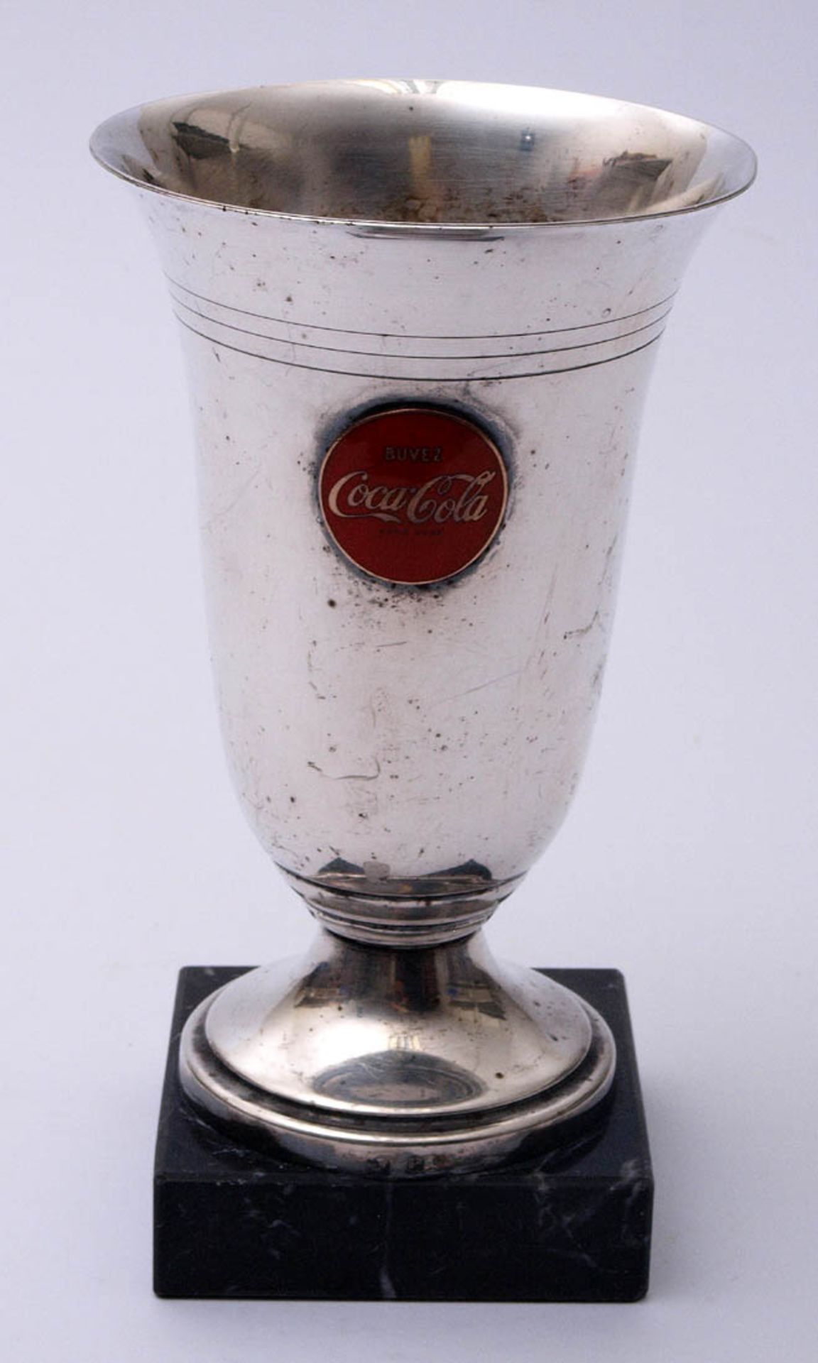 Pokal Auf schwarzem Marmorsockel, mit emailliertem Coca-Cola-Emblem. Metall, versilbert. H.16cm.