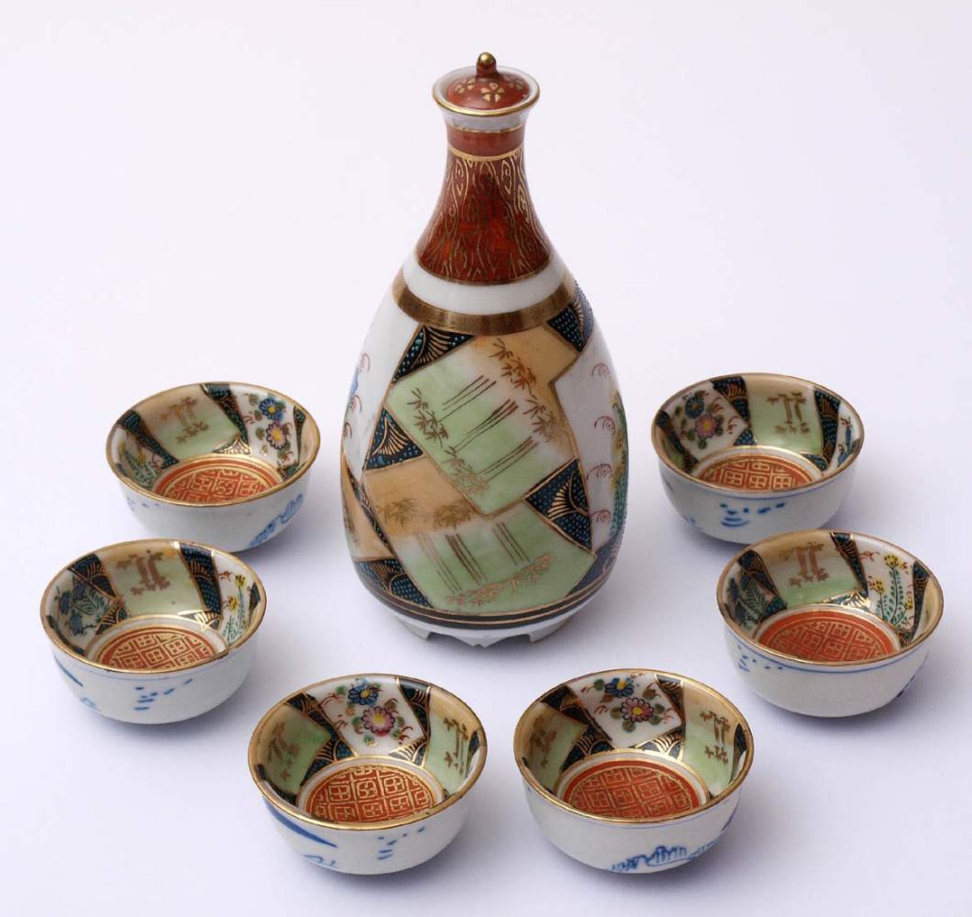 Sakegarnitur, JapanBestehend aus Sakeflasche mit Deckel und sechs Schälchen. Eisenrote Bodenmarke,