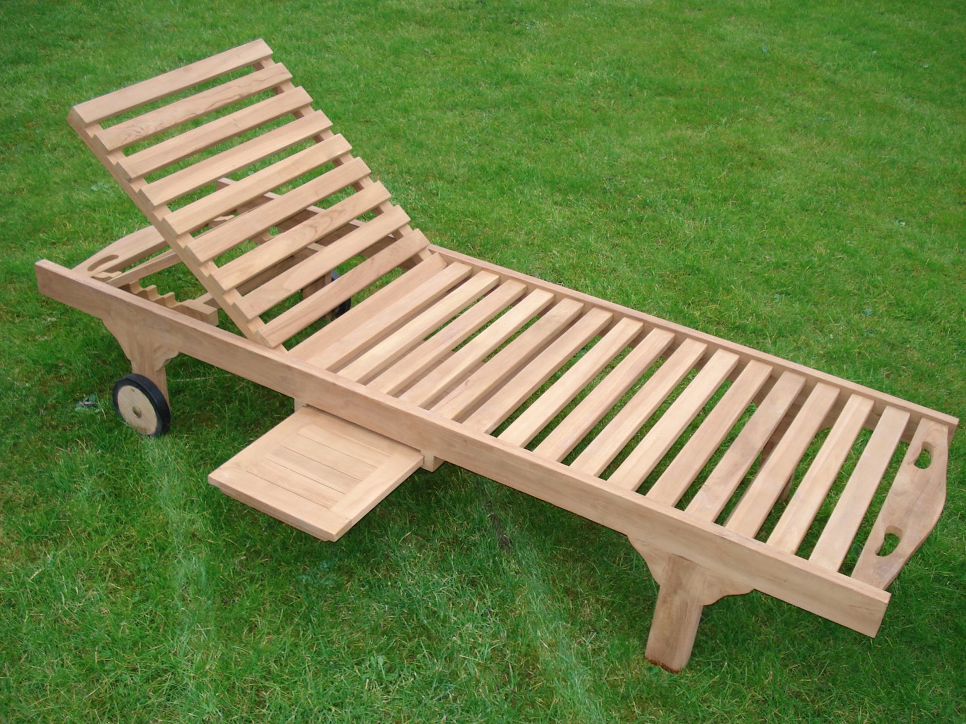 NEW PACKAGED SOLID TEAK SUNLOUNGER ON RUBBER BOUND TEAK WHEELS, WITH EXTENDING SIDE TABLE