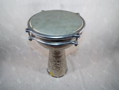 An unusual white metal djembe drum with embossed decoration,
