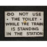 A cast iron sign marked 'Do not use the toilet while the train is standing in the station',