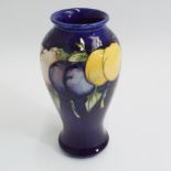 Moorcroft pottery vase decorated with lemons and plums, blue ground, signed to the base.  19cm high