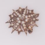 Edwardian pendant brooch of starburst form, set with half pearls and central diamond. 2.5 cms