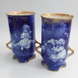 Pair of Royal Doulton blue and white vases of cylindrical form decorated with children and gilding.