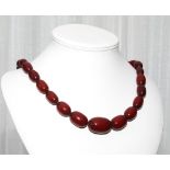 Graduated row of red amber beads, approx 68 cms long.