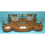 An oak desk stand, with a brass mount, set two inkwells, 20 cm wide