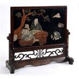 A Chinese hardstone table screen, decorated figures at a table, in a hardwood stand, 56 cm high  See