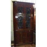 A 19th century mahogany floor standing corner cupboard, having a pair of bar glazed doors above a