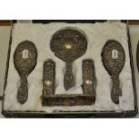 A silver six piece dressing table set, decorated stylised heads,