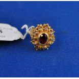 An Indian yellow coloured metal locket ring, set a central garnet,