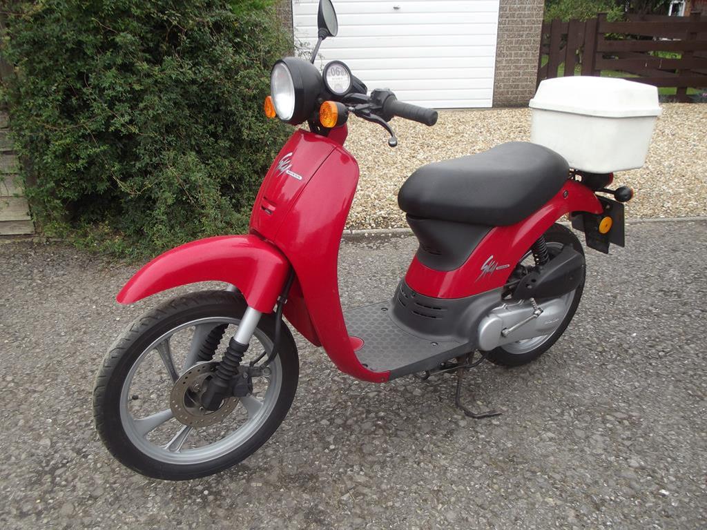 A 1999 Honda Sky SGX50 scooter, registration number T874 PDG, red.