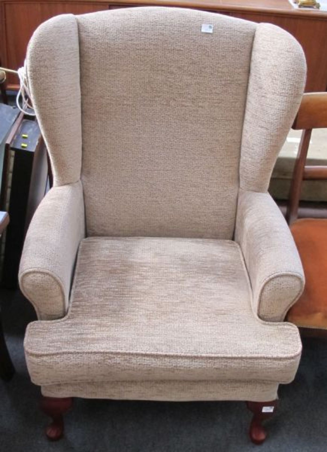 A Fawn Upholstered Wing Back Easy Armchair.  (est. £30-£50)