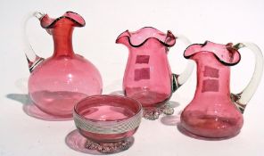 Three various cranberry glass jugs and a