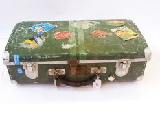 A tin suitcase bearing various luggage labels