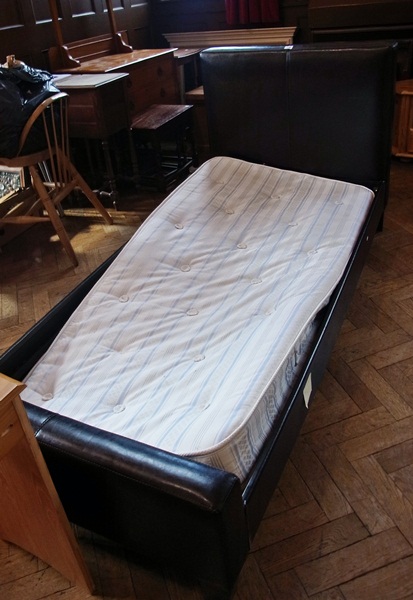 A modern black leatherette single bed wi