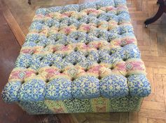 Large buttoned upholstered pouffe on box