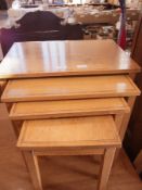 A nest of four pale oak side tables with