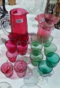 A selection of coloured glass items including a large cranberry glass water jug,