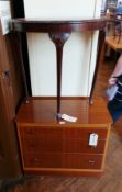 A teak cabinet with three graduated long drawers and a reproduction demi-lune side table