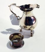 An old silver cream jug with cut card borders, scroll handle, raised on pad feet,