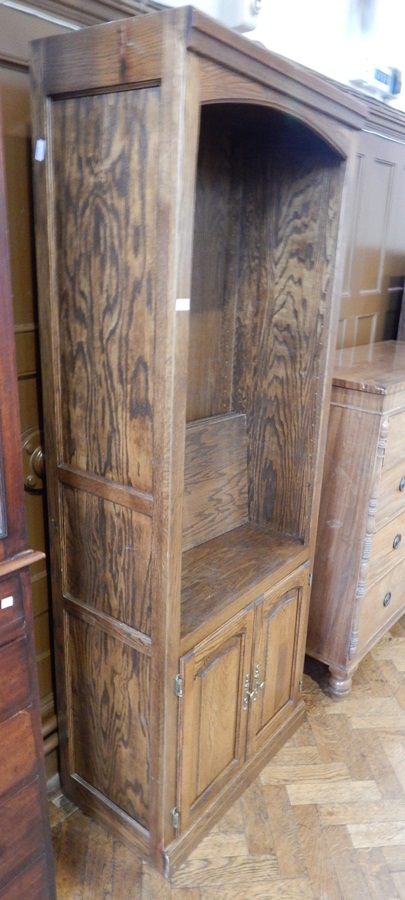 An oak-grained bookcase with adjustable shelves and cupboard with pair of panel door below,