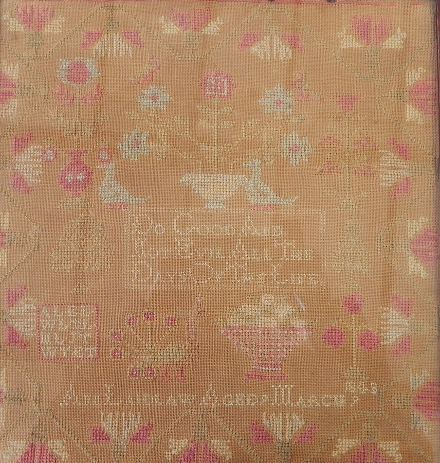 A sampler by Ann Laidlaw, aged 9, 1848/3(?), pink, cream and pale blue embroidery, 30cm x 28cm