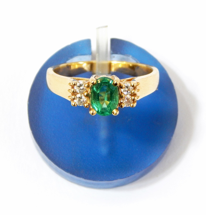 Emerald and diamond ring set central oval cut emerald flanked by two pairs of small diamonds  Live