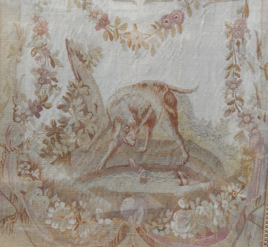 A fragment of woven material, possibly 18th century, showing a hunting dog with a hare, within a