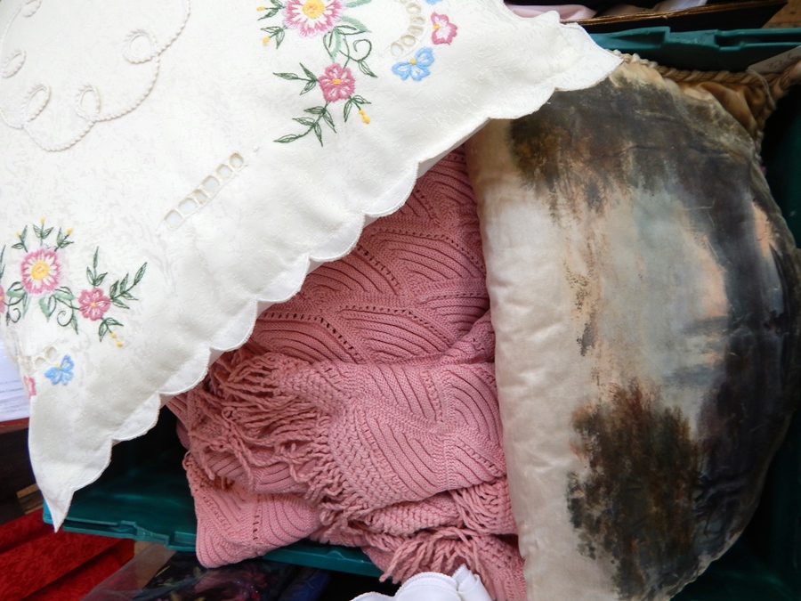 An embroidered cushion with a large possibly hand crocheted, salmon pink bedspread and satin cushion