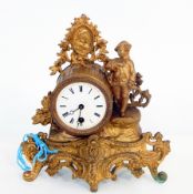 A French-style metal mantel timepiece in drum-shaped case, surmounted by figure and floral cresting,