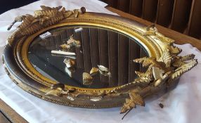 Oval gilt mirror with floral decoration to top and bottom