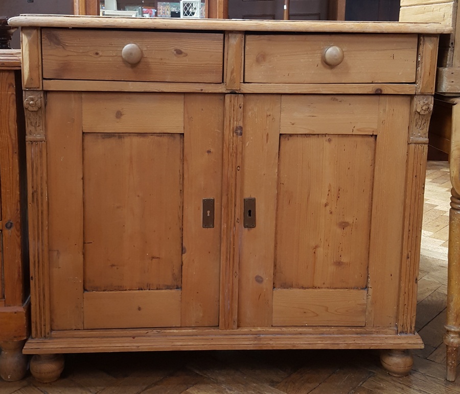 Old pine side cupboard with moulded top and two frieze drawers, cupboard below, on bun feet,