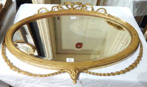 Oval gilded mirror with scroll top and floral bottom decoration