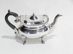 Edwardian silver teapot with gadrooned border, ebony handle, raised on paw feet, London 1902,