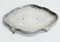 George III silver teapot stand of wavy oval form with bright-cut engraving, on raised feet,