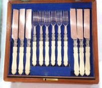 Set of 12 ivory-handled silver plated dessert knives and forks (one missing) in mahogany table top