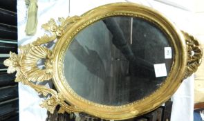 Oval mirror with gilded frame and floral and shell decoration to the top