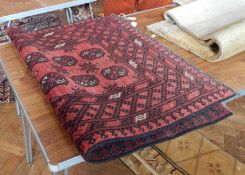 Wool rug, the red ground with elephant foot guls, geometric borders in black and cream,