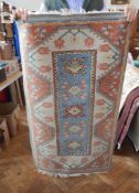 Wool rug with pale blue ground, shaped lozenge medallions and stylised floral border,