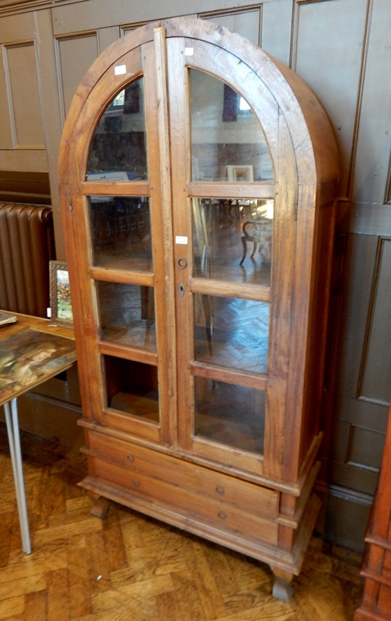 An Eastern hardwood glazed bookcase with domed top, pair of doors enclosing shelves,